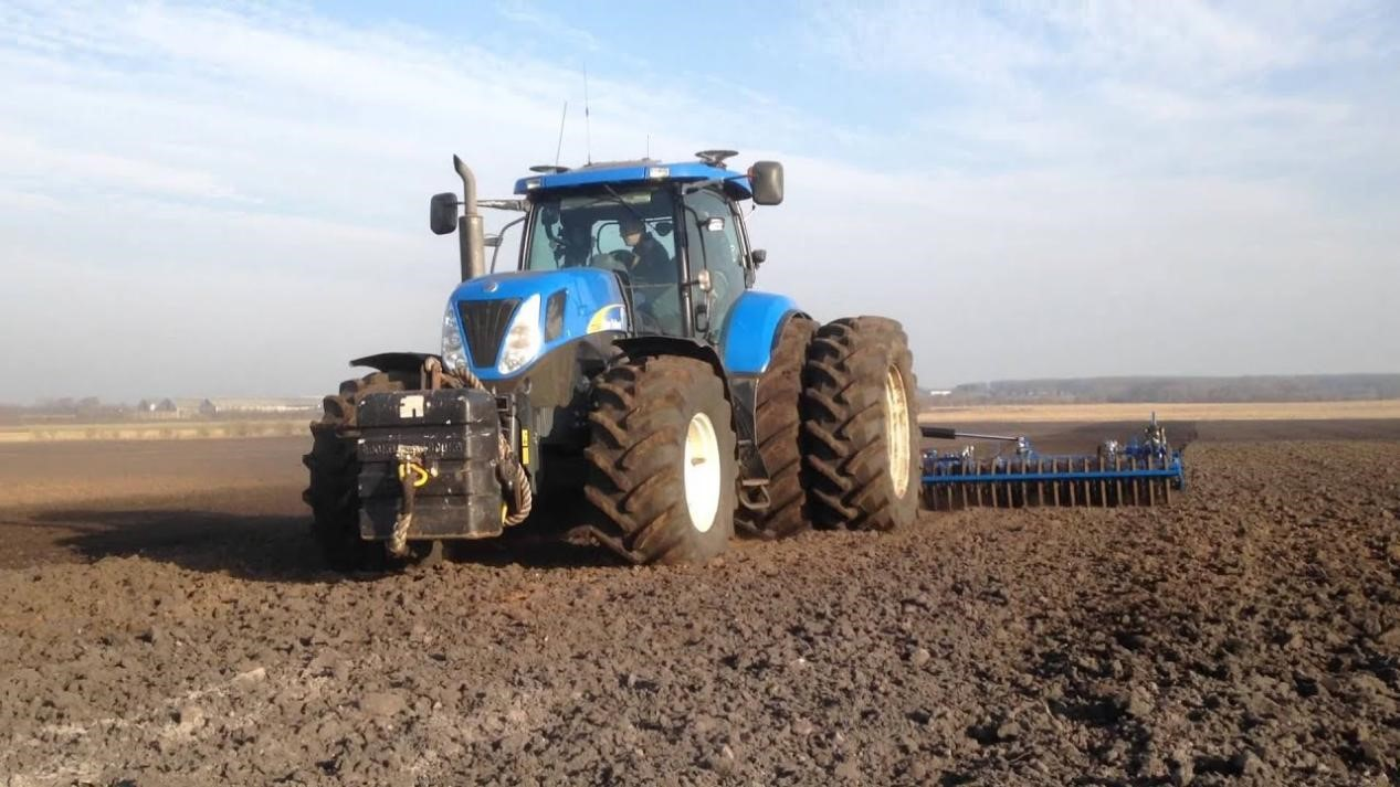 Kék traktor hátsó ikerkerekekkel szántóföldi munka közben